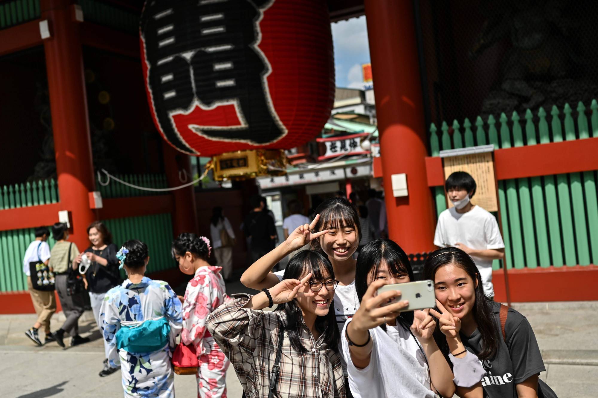 People pose at the entrance to Sensoji temple in Tokyo's Asakusa district on Tuesday. | AFP-JIJI
