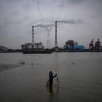 A man fishes in the Huangpu River near the Wujing Coal-Electricity Power Station in Shanghai. | AFP-JIJI
