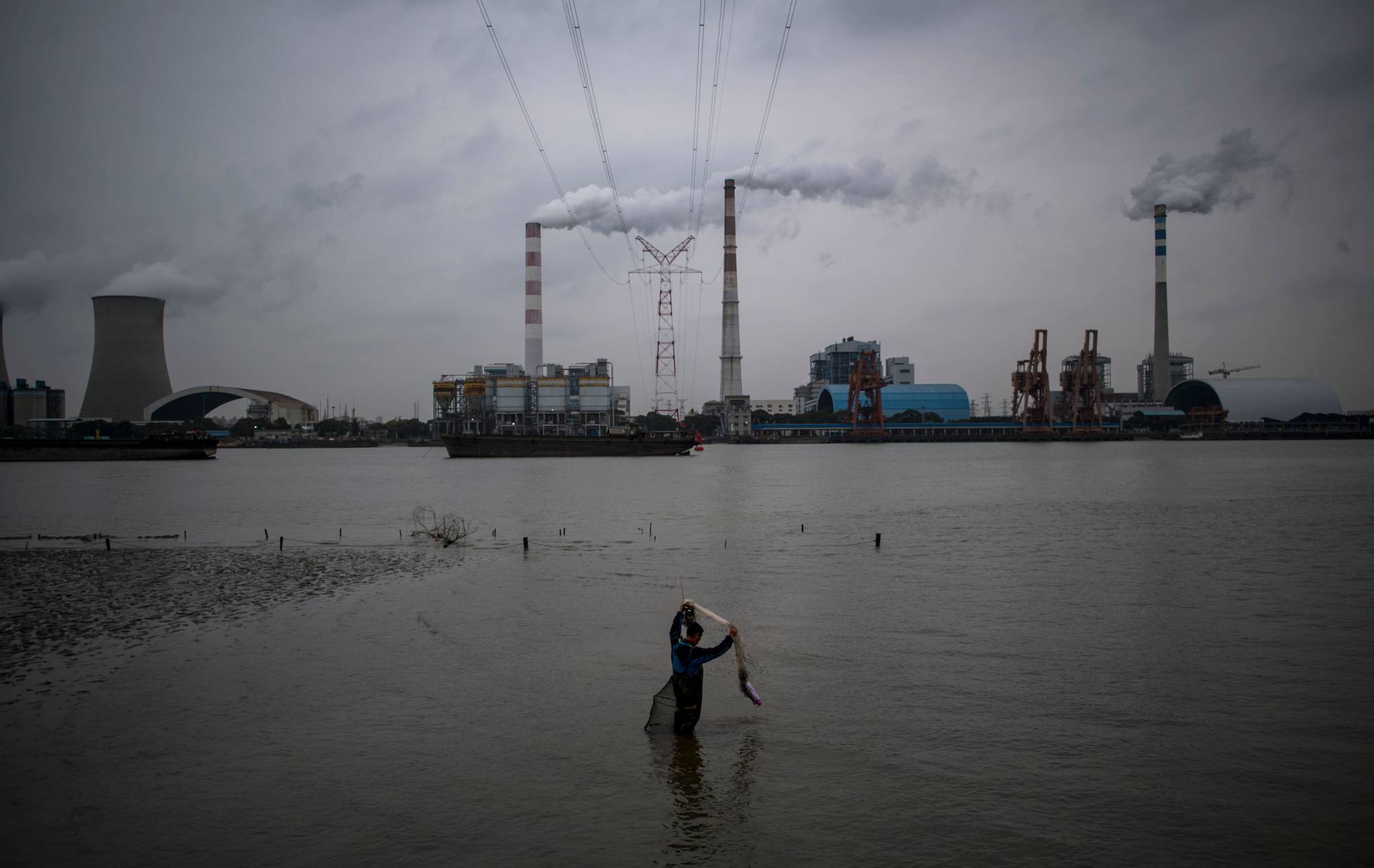 A man fishes in the Huangpu River near the Wujing Coal-Electricity Power Station in Shanghai. | AFP-JIJI