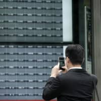 A man takes a photo of a blank electronic stock board at a securities firm in Tokyo on Thursday. Trading on the Tokyo Stock Exchange was suspended because of a problem with the system for relaying market information. | AP