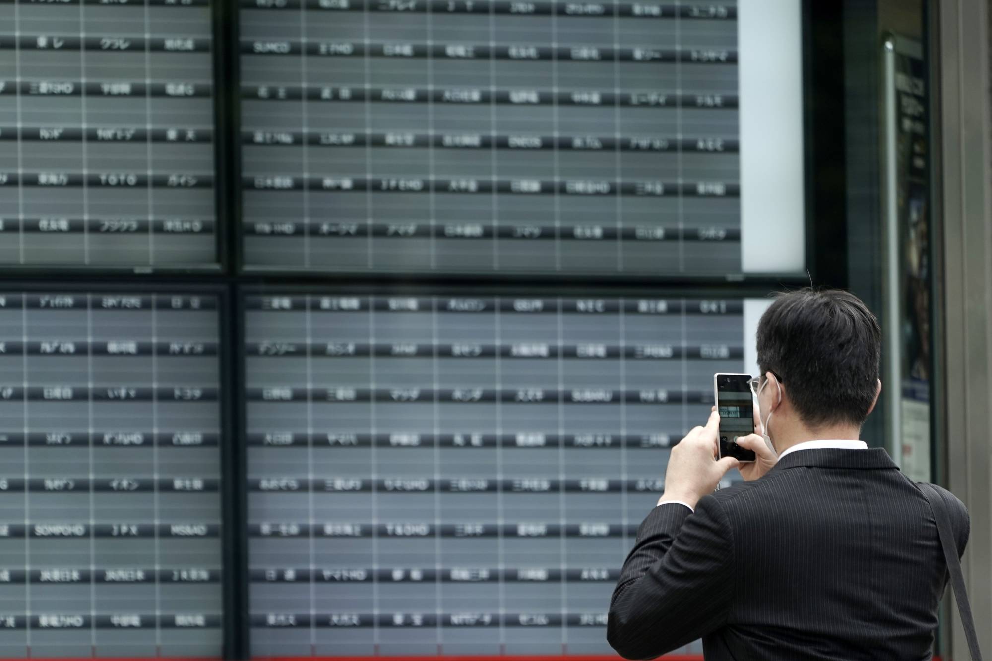 A man takes a photo of a blank electronic stock board at a securities firm in Tokyo on Thursday. Trading on the Tokyo Stock Exchange was suspended because of a problem with the system for relaying market information. | AP
