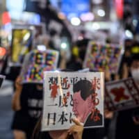 People chant slogans and hold placards during an anti-China protest to mark the 71st anniversary of the founding of the People\'s Republic of China in Tokyo\'s Shinjuku district on Saturday. | AFP-JIJI