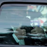 U.S. President Donald Trump gives a thumbs-up from a car as he rides in front of Walter Reed National Military Medical Center, where he is being treated for the coronavirus, in Bethesda, Maryland, on Sunday. | REUTERS