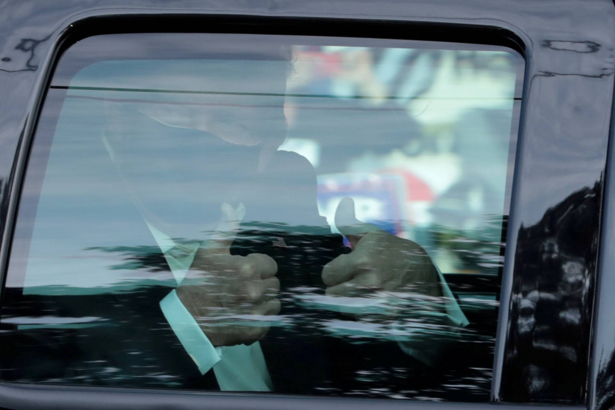 U.S. President Donald Trump gives a thumbs-up from a car as he rides in front of Walter Reed National Military Medical Center, where he is being treated for the coronavirus, in Bethesda, Maryland, on Sunday. | REUTERS
