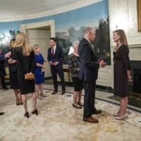 U.S. President Donald Trump and first lady Melania Trump greet guests including Judge Amy Coney Barrett (right) at the White House on Sept. 26. Two weeks after the Centers for Disease Control and Prevention took down a statement about airborne transmission of the coronavirus, the agency on Monday replaced it with language citing new evidence that the virus can spread beyond six feet indoors. 
 | DOUG MILLS / THE NEW YORK TIMES
