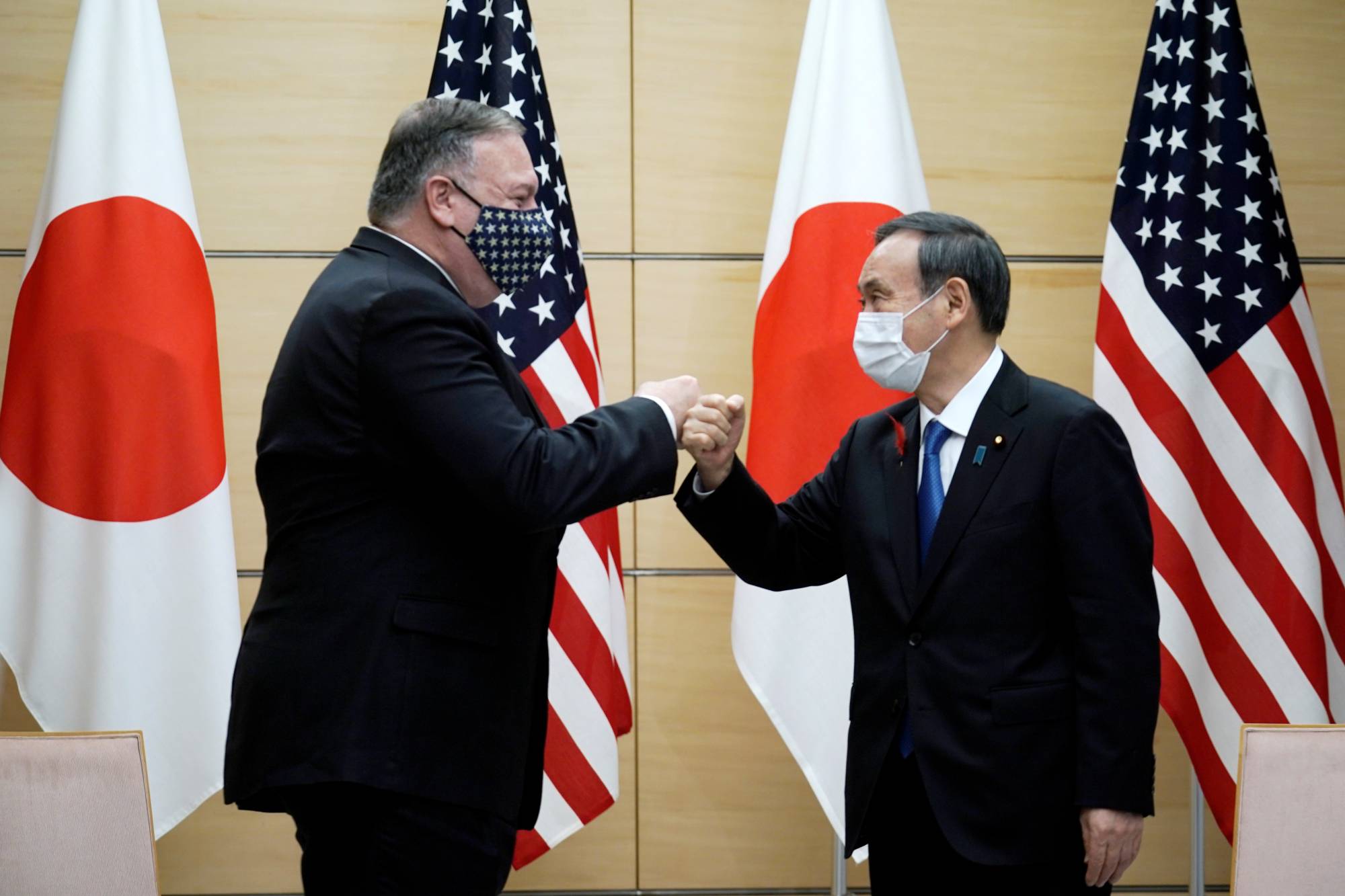 Prime Minister Yoshihide Suga and U.S. Secretary of State Mike Pompeo greet each other prior to their meeting at the Prime Minister's Office on Tuesday. | POOL / VIA REUTERS