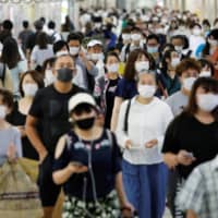 Passengers wearing protective face masks make their way to work amid the COVID-19 pandemic in September. | REUTERS