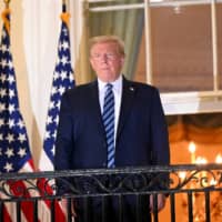 U.S. President Donald Trump poses atop the Truman Balcony of the White House in Washington after returning from his hospitalization at Walter Reed Medical Center on Monday. | REUTERS