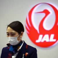 No masking progress: An Japan Airlines employee wears a protective mask at Kansai International Airport in Osaka. | REUTERS