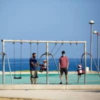 Parents play with their toddlers at a playground by the beach in Israel last month.  | REUTERS