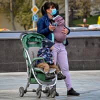A mother and her babies wait for a bus in central Moscow last month.  | AFP-JIJI
