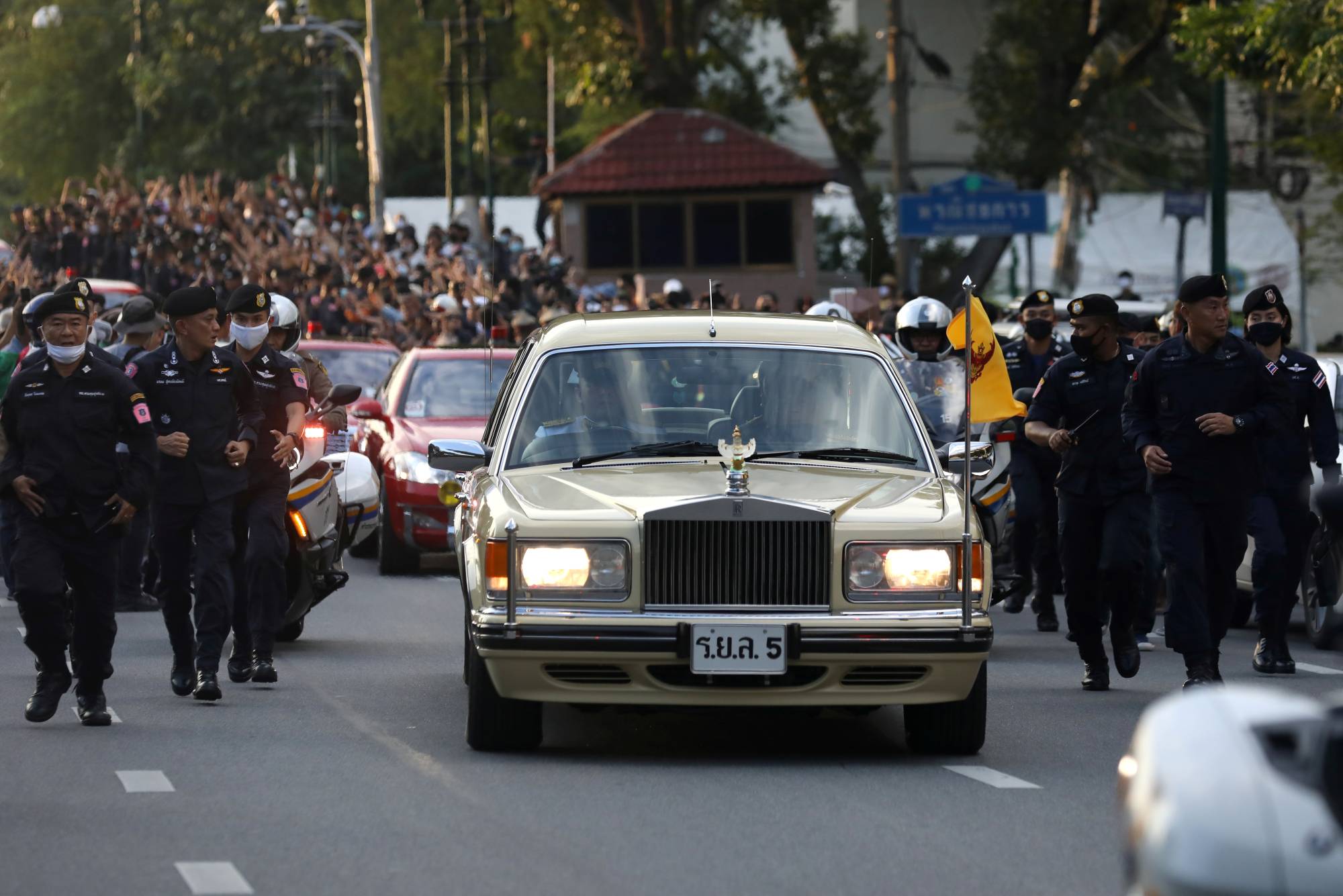 A vehicle carrying Thailand's King Maha Vajiralongkorn and Queen Suthida drives past an anti-government mass protest in Bangkok on Wednesday. | REUTERS 