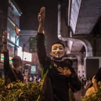 Anti-government protesters raise a three finger salute that has become a symbol of anti-government defiance in Bangkok on Friday.  | ADAM DEAN/THE NEW YORK TIMES