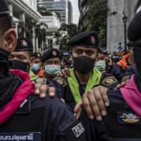 Royal Thai Police link arms to stop anti-government protesters during a protest at  Ratchaprasong intersection in the commercial center of Bangkok on Thursday.  | ADAM DEAN/THE NEW YORK TIMES