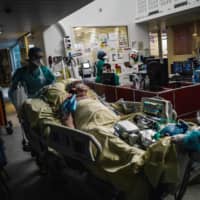 Medical workers transport a patient in the intensive care unit of Lariboisiere Hospital in Paris on Wednesday.  | AFP-JIJI