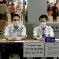 Hong Kong health workers at a border checkpoint between
Hong Kong and mainland China\'s Shenzhen in 2003 | REUTERS