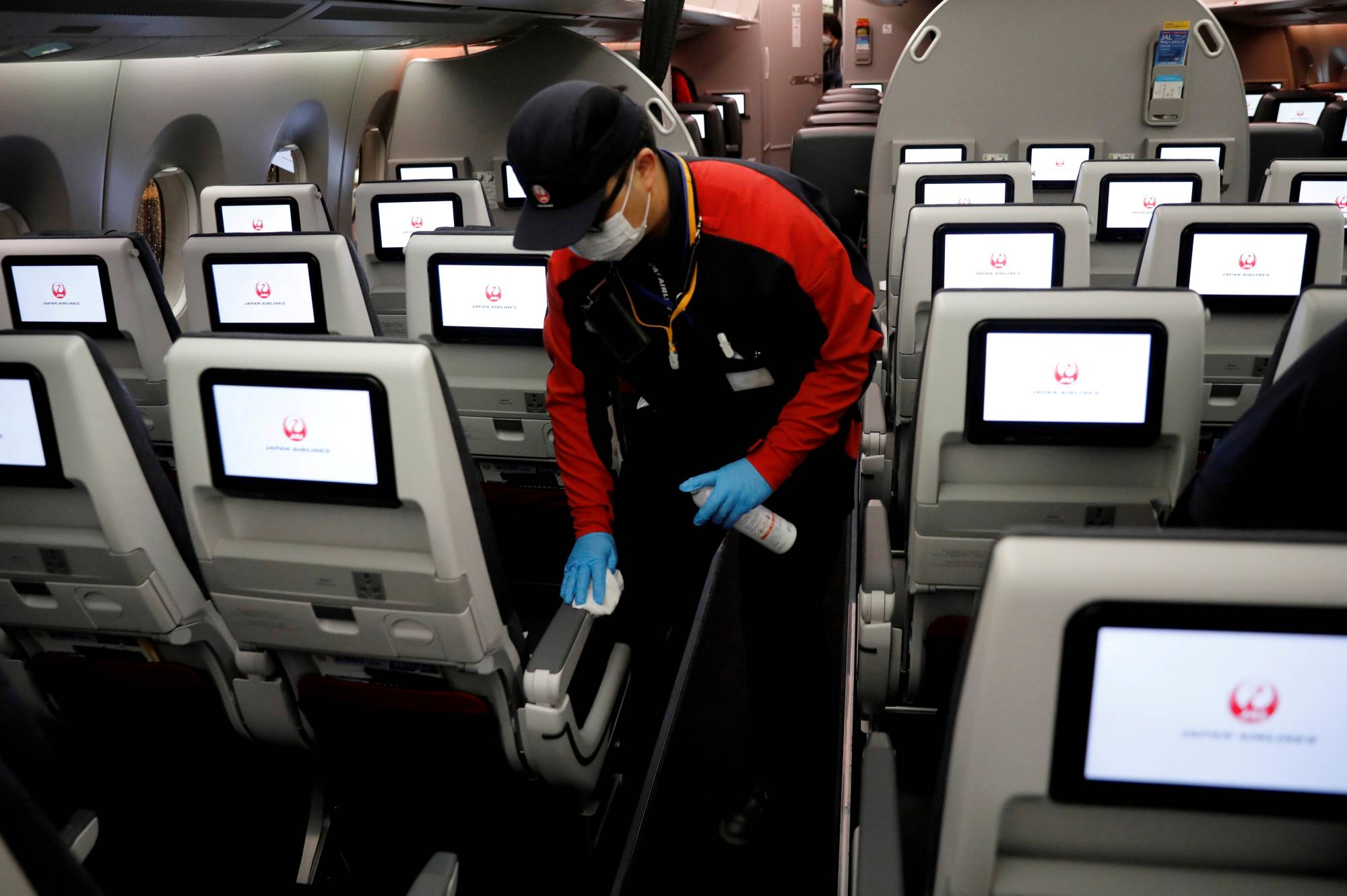 A Japan Airlines staff member cleans the cabin of a plane at Haneda Airport in May.  | REUTERS 