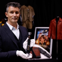 Stephen Lane, CEO of Prop Store, poses with Obi-Wan Kenobi\'s Hero Lightsaber from \"Star Wars: Revenge of the Sith,\" at a preview of a movie and TV memorabilia auction in Rickmansworth, Britain. | REUTERS