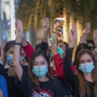 Pro-democracy activists flash three-fingered salutes while listening to the national anthem outside of the Siam Paragon shopping mall in Bangkok on Tuesday. | AP