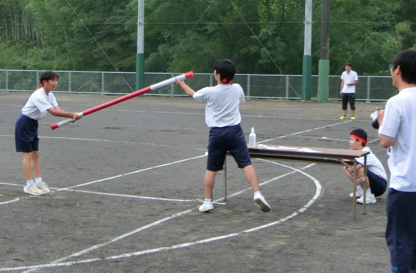 Two students from Shimizuojima Junior High School in the city of Shizuoka pass a long baton between them in a relay race during sports day in September. | SHIMIZUOJIMA JUNIOR HIGH SCHOOL / VIA CHUNICHI SHIMBUN