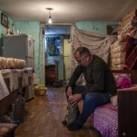 Ceyhun Seymur Khudiyev, 45, sits in his room where his family live in an unfinished school in Baku on Oct. 19. | IVOR PRICKETT / THE NEW YORK TIMES