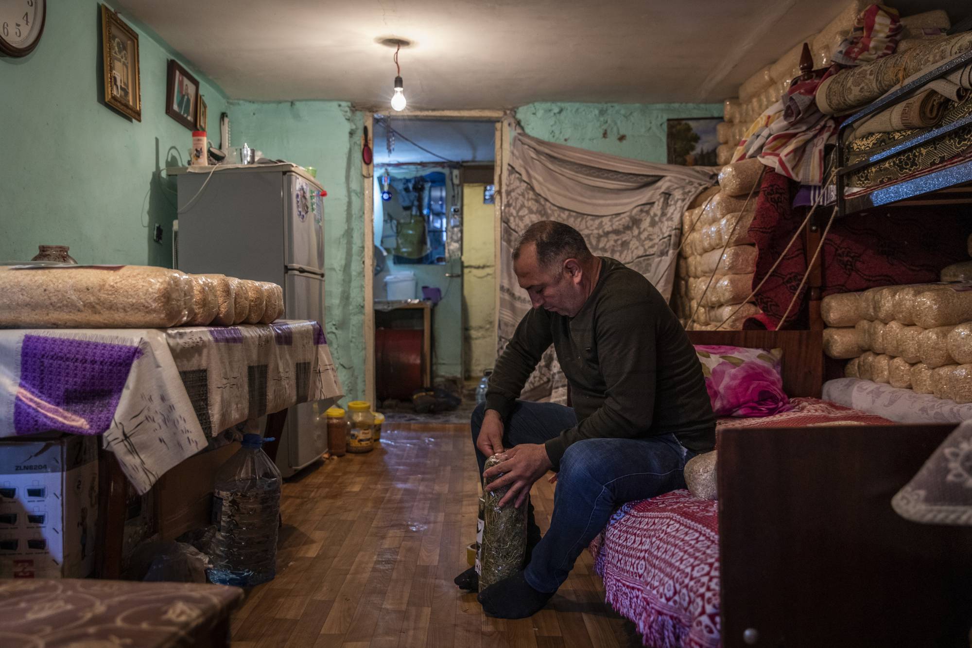 Ceyhun Seymur Khudiyev, 45, sits in his room where his family live in an unfinished school in Baku on Oct. 19. | IVOR PRICKETT / THE NEW YORK TIMES