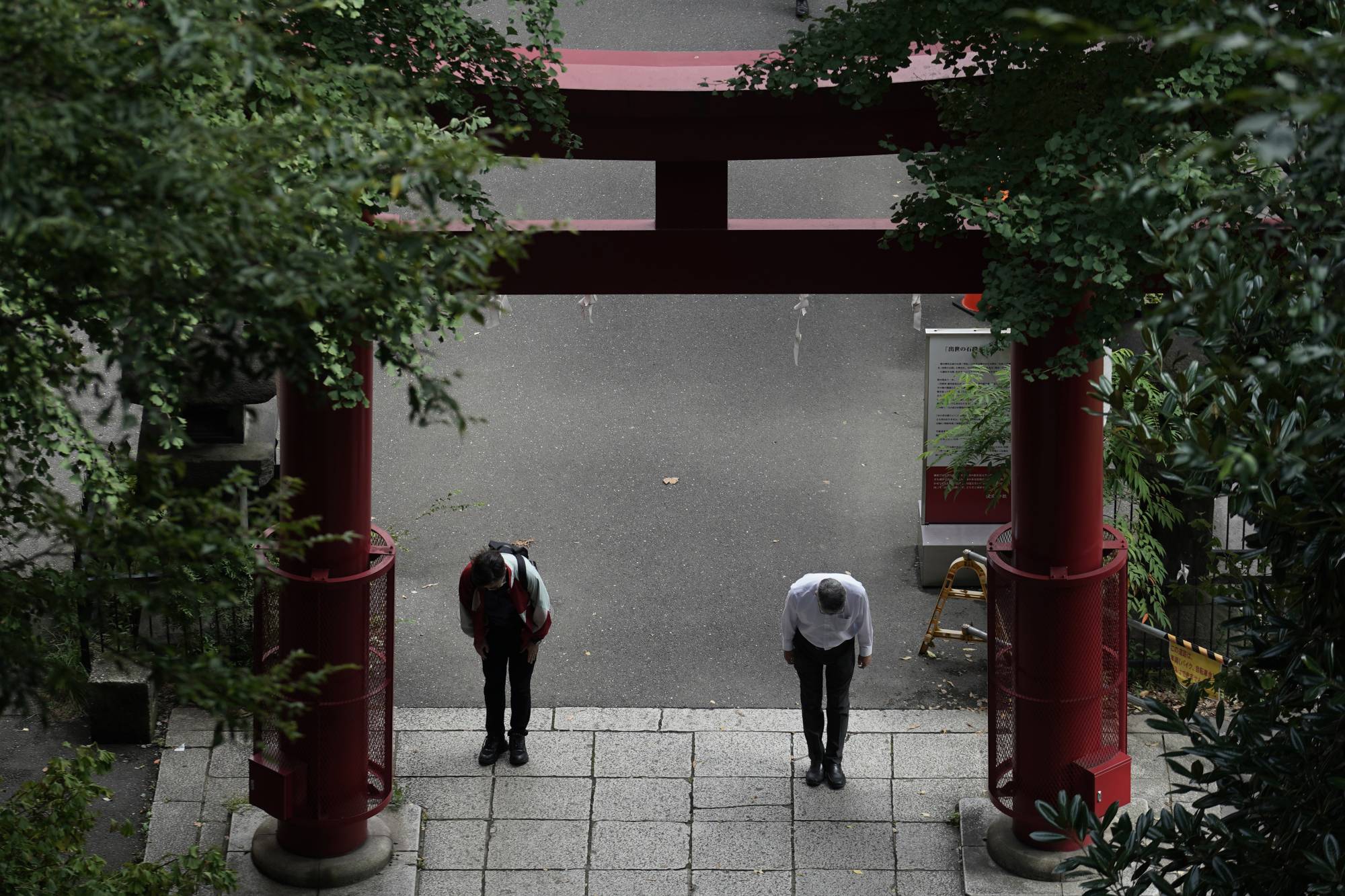 People wearing protective masks to help curb the spread of the COVID-19 virus bow before climbing the steep stairs of a shrine on Oct. 12 in Tokyo. | AP