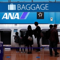 Passengers deposit their baggage at a check-in counter of All Nippon Airways at Haneda Airport in Tokyo on Friday. | REUTERS