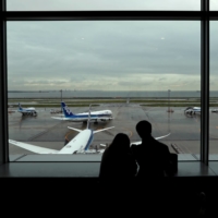 A couple watches ANA aircraft at Haneda Airport in Tokyo on Friday. | REUTERS