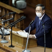 Yoshihide Suga, Prime Minister, wears a protective mask as he delivers his policy speech during an extraordinary session at the Lower House of the Diet in Tokyo on Monday. | BLOOMBERG