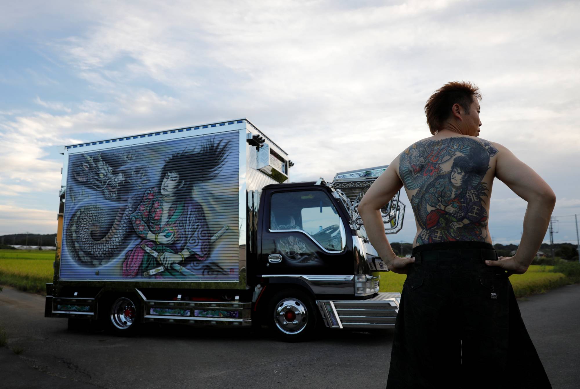 Truck driver Hideyuki Haga, 44, poses in front of his truck, which is decorated with the same design as the tattoo on his back, in Hiki, Saitama Prefecture, on Sept. 3. | REUTERS