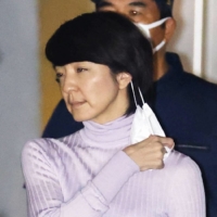 Anri Kawai takes off a face mask before bowing after she was released on bail from the Tokyo Detention House on Tuesday night. | KYODO