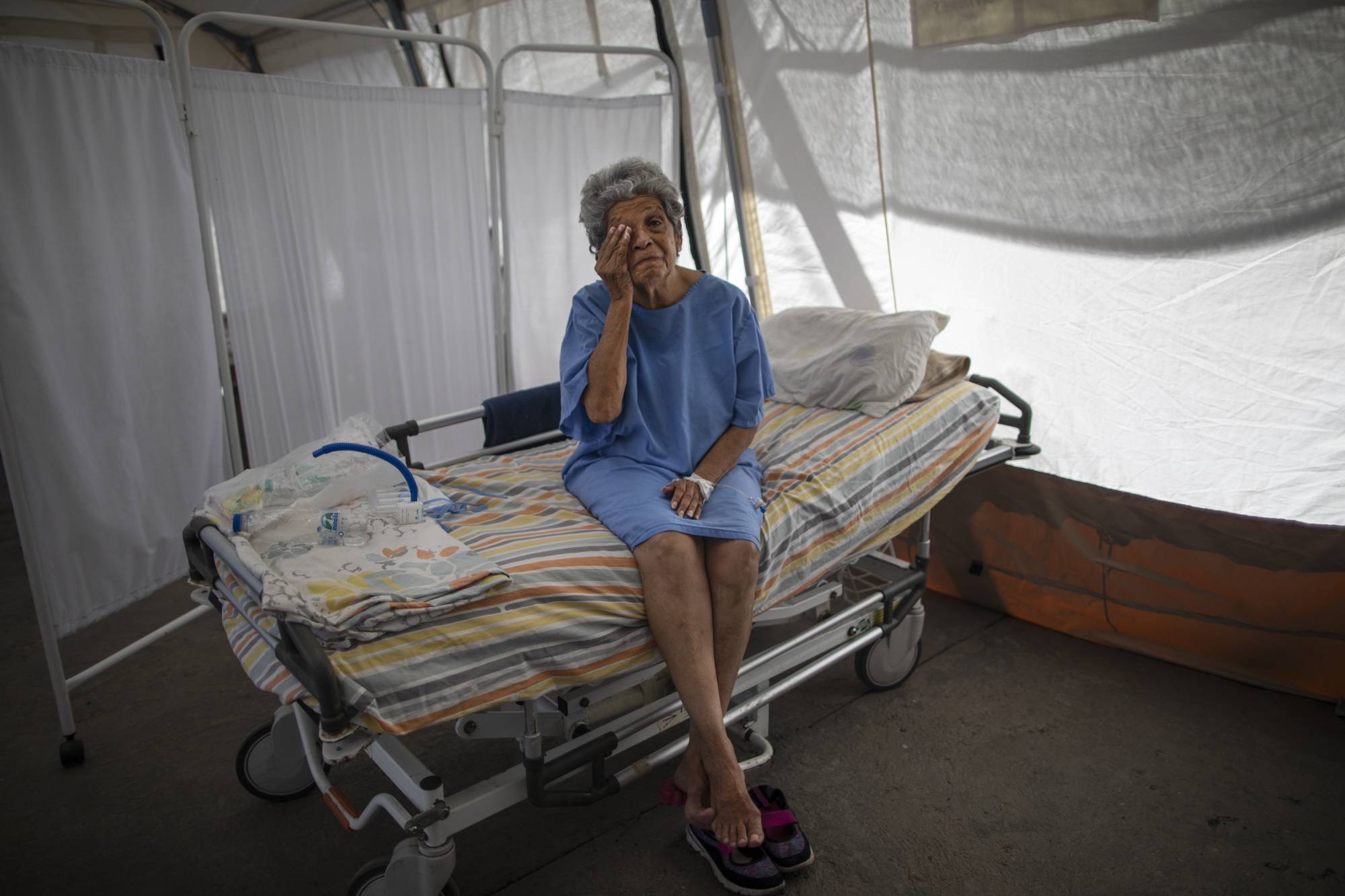 A 76-year-old COVID-19 patient wipes away tears at a public hospital in Caracas.  | AP