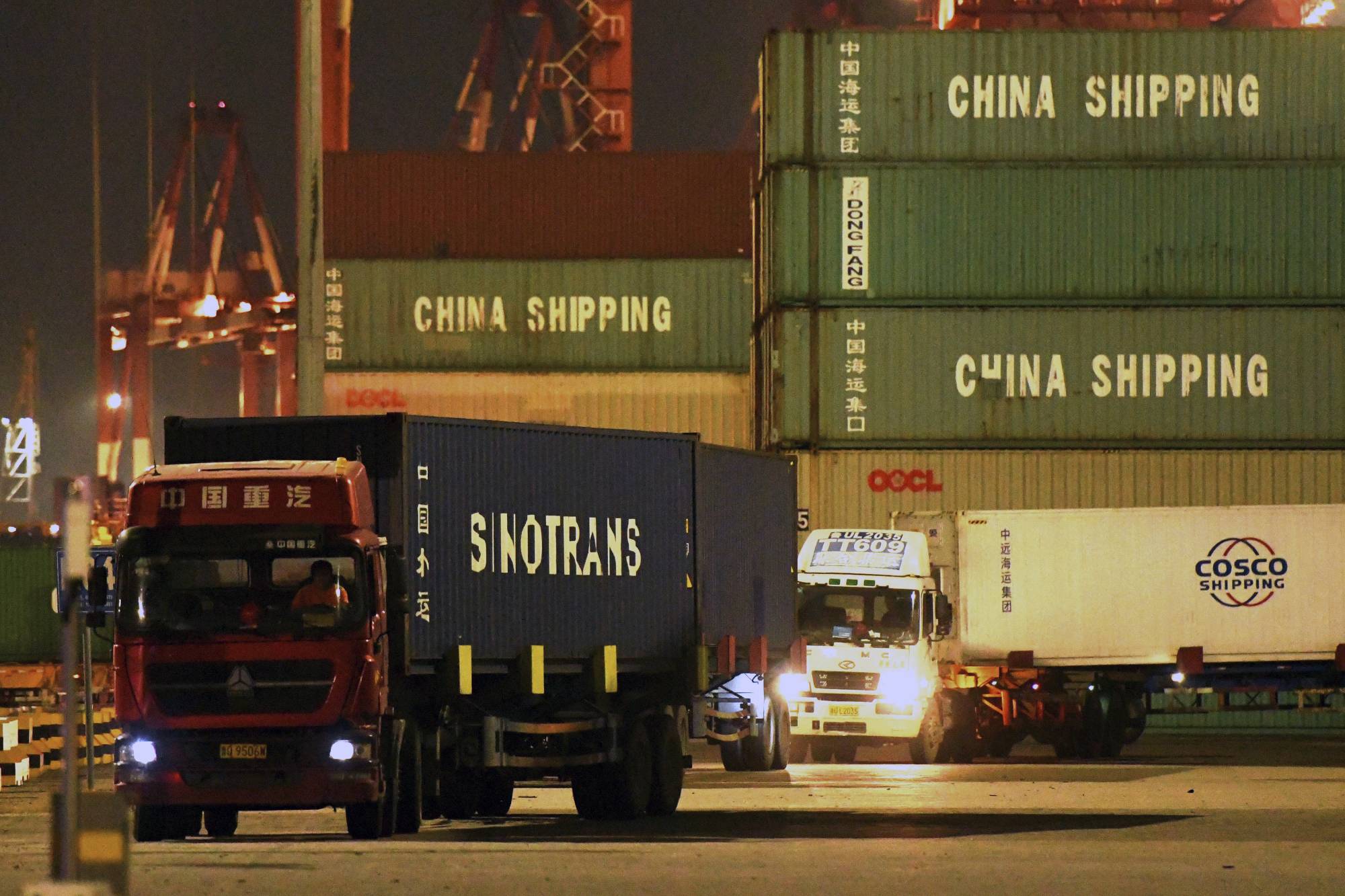 Trucks transport shipping containers at a dockyard in Qingdao in east China's Shandong province last month.  | CHINATOPIX / VIA AP