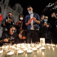 People lights candles outside the Notre-Dame de l\'Assomption Basilica in Nice on Thursday in tribute to the three victims of a knife attacker inside a church in the city.  | AFP-JIJI