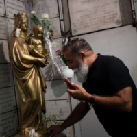 A Muslim man lays a white flower at the Notre-Dame de la Garde basilica in Marseille, France, on Thursday during a gathering to pay tribute to the victims of a knife attack inside a church in Nice. | AFP-JIJI