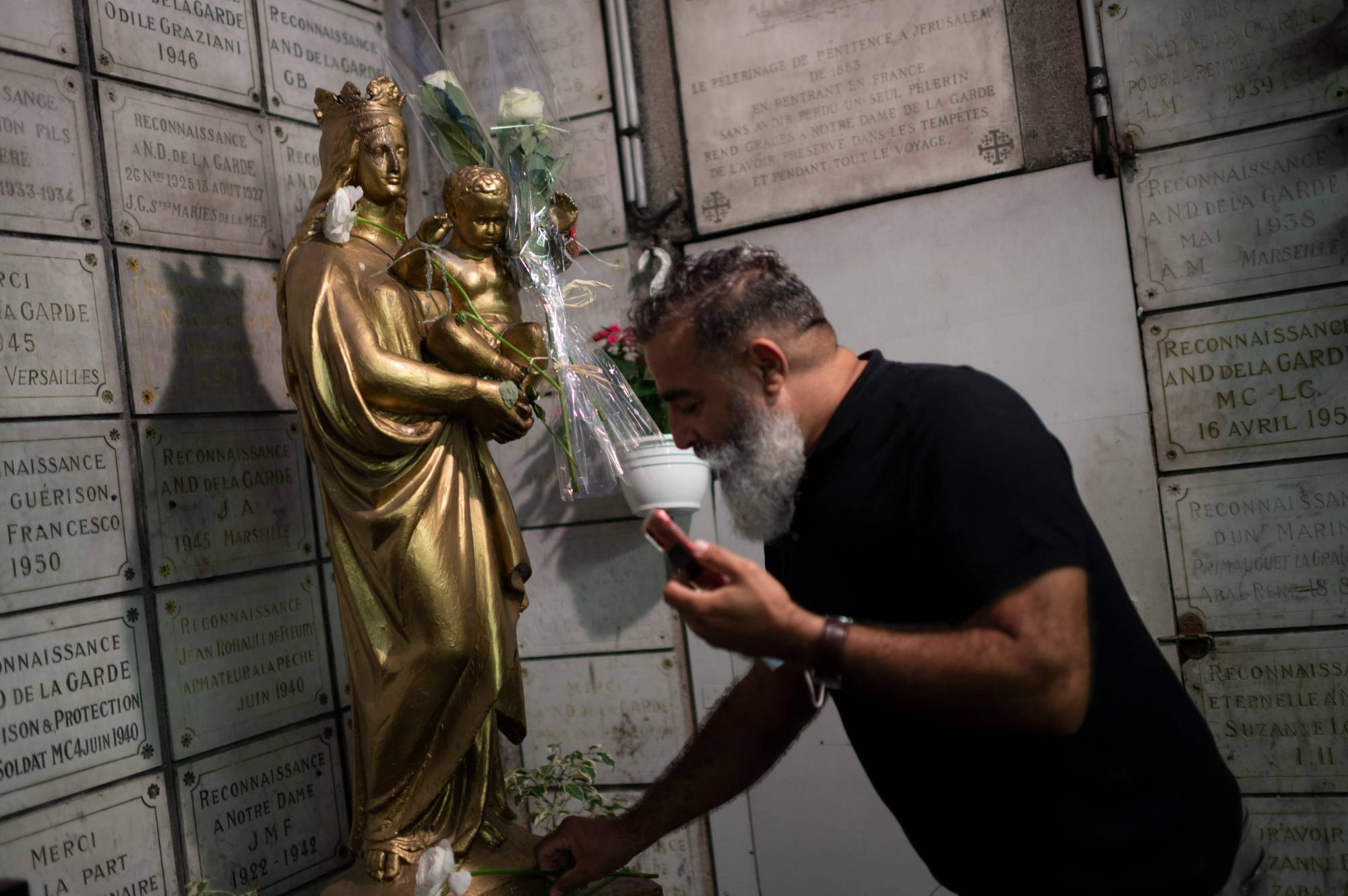 A Muslim man lays a white flower at the Notre-Dame de la Garde basilica in Marseille, France, on Thursday during a gathering to pay tribute to the victims of a knife attack inside a church in Nice. | AFP-JIJI