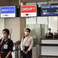 Airline staff are seen at a boarding gate for international flights at Haneda Airport earlier this month. | KYODO
