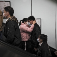 Commuters take an escalator as they exit a subway station during the morning rush hour in Beijing on Thursday. In China, residents are once again flocking into malls, bars, concert halls and hair salons, while schools, subways and offices are crowded. | AP