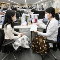 Staff at the Environment Ministry use blankets as the annual \"Warm Biz\" energy-saving campaign kicked off Monday. | KYODO