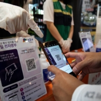 A visitor scans a QR code to log his entry at the Seongdong district government office building in Seoul. | BLOOMBERG 
