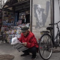 A man reads a newspaper at a newsstand in Beijing in March 2020 | GILLES SABRIÉ / THE NEW YORK TIMES