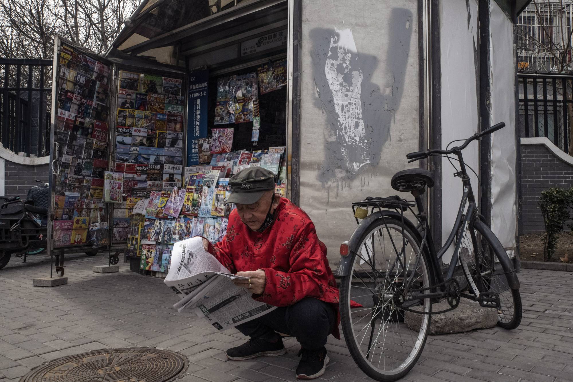 A man reads a newspaper at a newsstand in Beijing in March 2020 | GILLES SABRIÉ / THE NEW YORK TIMES