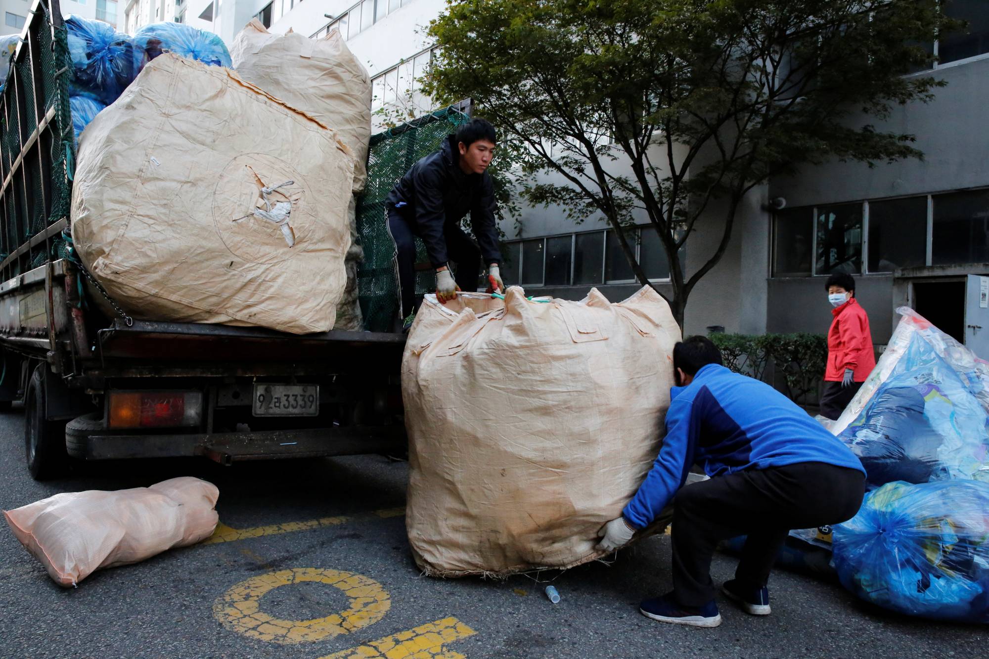 Lee Yong-gi, owner of a recycling facility, collects sacks of recycling garbage in a residential area of Seoul last month.  | REUTERS