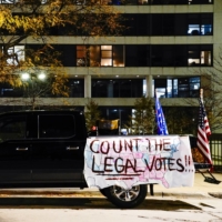 A banner reading \"Count the Legal Votes\" and a U.S. and Trump flag hang from a pickup truck at a protest in Milwaukee, Wisconsin, on Thursday. | REUTERS