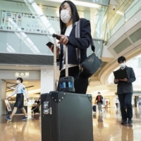 A woman pulls an artificial intelligence suitcase that is designed to assist visually impaired people, at an airport in Japan on Monday. | KYODO