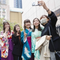 Graduates of Kyoritsu Women\'s University in Tokyo pose for a photograph at a graduation ceremony held on Tuesday. The ceremony was delayed due to the coronavirus. | KYODO