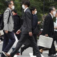 People walk Monday in Tokyo. Urban areas have been seeing high numbers of infections lately, with the nationwide daily figure at 1,141 on Friday, a day after the country\'s tally topped 1,000 for the first time since Aug. 21. | AP