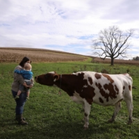 Rebecca Seidel and her son Adlai Seidel-Semsick greet a cow at their farm in Womelsdorf, Pennsylvania, on Oct. 27.  | REUTERS