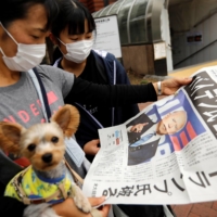 People read an extra edition of a newspaper reporting that Democratic U.S. presidential nominee Joe Biden is projected to win the 2020 U.S. presidential election in Tokyo on Sunday. | REUTERS